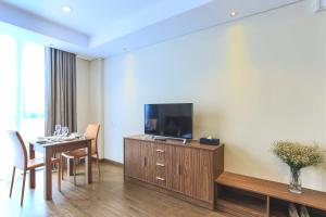 a hotel room with a dining table and a flat screen tv at Aurora Serviced Apartments in Ho Chi Minh City