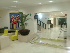 a lobby with a potted plant and a painting on the wall at We Hotel Aeropuerto in Mexico City