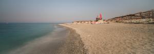 a beach with a group of houses and the water at Palmed Hotel in Gizzeria