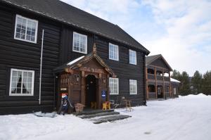 un grande edificio in legno con una porta nella neve di Toftemo Turiststasjon a Dovre