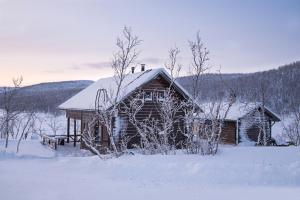 een blokhut met sneeuw op het dak bij Saivaara Cottages in Kilpisjärvi