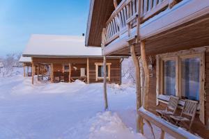 een blokhut in de sneeuw met twee stoelen voor bij Saivaara Cottages in Kilpisjärvi