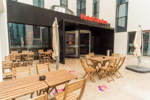 a restaurant with wooden tables and chairs in front of a building at Star inn Lisbon Airport in Lisbon