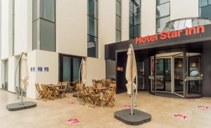 a hotel star inn with tables and chairs and umbrellas at Star inn Lisbon Airport in Lisbon