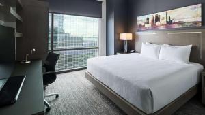 een hotelkamer met een bed, een bureau en een raam bij Hyatt House Jersey City in Jersey City