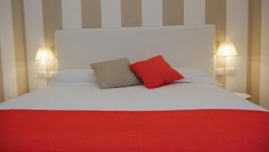 a large white bed with a red pillow on it at Domus Nova in Reggio di Calabria