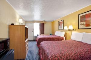 a hotel room with two beds and a flat screen tv at Days Inn by Wyndham Knoxville West in Knoxville