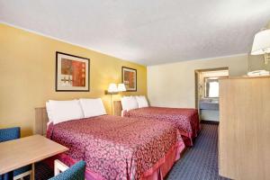 a hotel room with two beds and a table at Days Inn by Wyndham Knoxville West in Knoxville