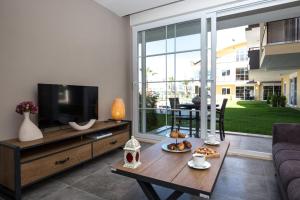 uma sala de estar com uma televisão e uma mesa em Lara Beach Homes em Antália