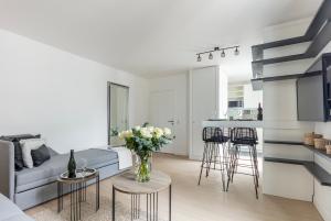 uma sala de estar com um sofá e uma mesa com flores em Résidence Palais Étoile em Paris