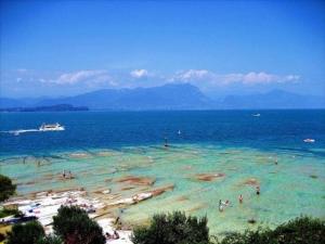 un groupe de personnes dans l'eau d'une plage dans l'établissement Villa Paradiso, à Sirmione