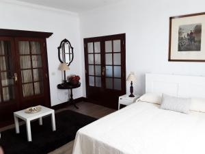 a bedroom with a white bed and a table at La Chimenea Verde in Tacoronte