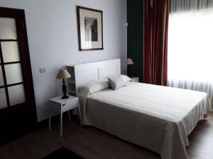 a bedroom with a white bed and a window at La Chimenea Verde in Tacoronte