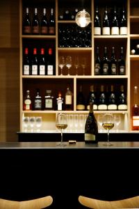 two glasses of wine sitting on a bar with bottles at HANNONG Hotel & Wine Bar in Strasbourg