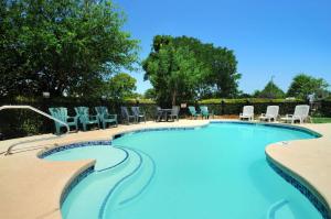 een groot zwembad met stoelen en tafels bij Microtel Inn & Suites by Wyndham Arlington/Dallas Area in Arlington