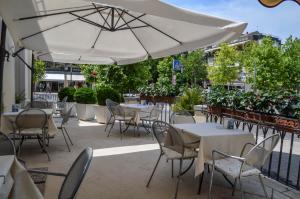 un patio con tavoli, sedie e ombrellone di Hotel Le Boulevard a Lido di Venezia