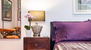 a bedroom with a purple bed and a lamp on a night stand at Romantic Bungalow in Notting Hill in London