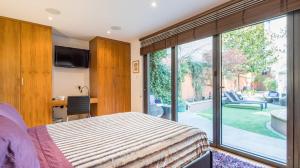 a bedroom with a bed and a large glass window at Romantic Bungalow in Notting Hill in London