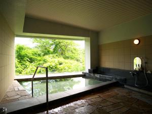 a bathroom with a pool of water with a window at Wisterian Life Club Usami in Ito