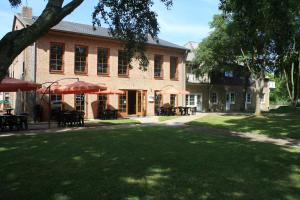 a building with tables and umbrellas in front of it at Pension Treenehof in Friedrichstadt