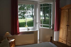 a bedroom with a window with red curtains and a bed at Pension Treenehof in Friedrichstadt