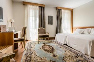 Habitación de hotel con cama, silla y escritorio. en Gran Hotel La Perla, en Pamplona