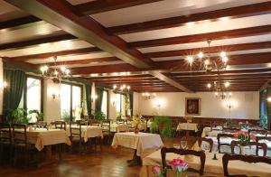 une salle à manger avec des tables, des chaises et des lustres dans l'établissement Auberge De La Foret - Logis, à Vendenheim