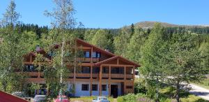 una grande casa in legno con macchine parcheggiate di fronte di Solbjørnlia Apartments a Trysil