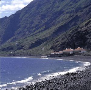 a rocky beach with a building on the side of a mountain at Parador de El Hierro in Las Casas