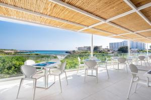 a patio with tables and chairs and a view of the ocean at Fergus Style Carema Beach in Cala'n Bosch