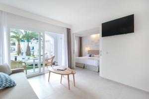 a hotel room with a bed and a living room at Fergus Style Carema Beach in Cala'n Bosch