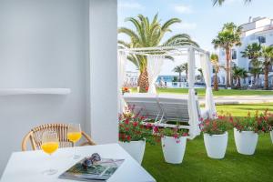 a table with a glass of wine and a white pergola at Fergus Style Carema Beach in Cala'n Bosch