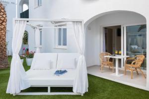 a white bed on a patio with a table at Fergus Style Carema Beach in Cala'n Bosch