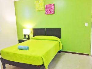 a green bedroom with a large bed with a yellow blanket at Hotel Plazha in Tuxtla Gutiérrez