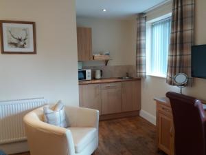 a living room with a chair and a kitchen at The Stables - Deer Park Farm in Solihull