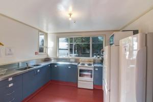 a kitchen with blue cabinets and a white refrigerator at The Flaming Kiwi Backpackers in Queenstown