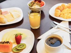 un tavolo con piatti per la colazione e un bicchiere di succo d'arancia di ibis Canoas Shopping a Canoas