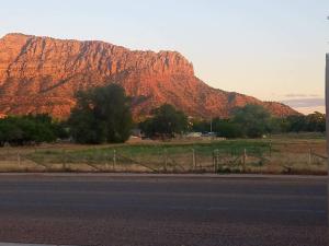 Blick auf einen Berg mit einem Zaun und einer Straße in der Unterkunft Zion's Most Wanted Hotel in Hildale