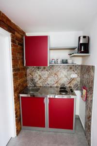 cocina con armarios rojos y pared de ladrillo en Apartman Kupa, en Karlovac