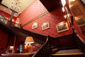 une femme assise à une table dans un escalier d'un bâtiment dans l'établissement Coulsdon Manor Hotel and Golf Club, à Croydon