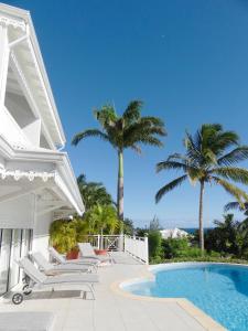 une maison blanche avec une piscine et des palmiers dans l'établissement Hôtel Amaudo, à Saint-François