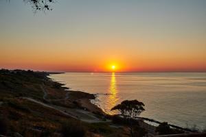 zachód słońca nad oceanem z drzewem na pierwszym planie w obiekcie Villaggio L'Oasi w mieście Isola Capo Rizzuto