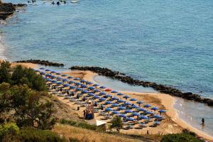 plaża z niebieskimi parasolami i oceanem w obiekcie Villaggio L'Oasi w mieście Isola Capo Rizzuto