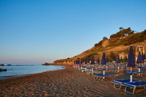 plaża z leżakami i parasolami oraz ocean w obiekcie Villaggio L'Oasi w mieście Isola Capo Rizzuto