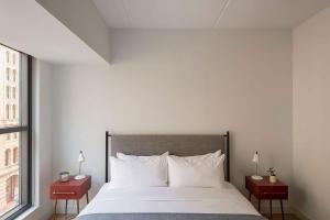 a bedroom with a large white bed with two tables at ROOST East Market in Philadelphia