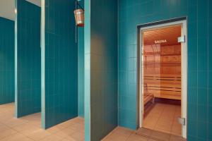 een badkamer met blauwe betegelde muren en een sauna bij Corendon Urban Amsterdam Schiphol Airport Hotel in Badhoevedorp