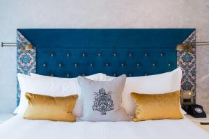 a bed with a blue head board and pillows at Vintry & Mercer Hotel - Small Luxury Hotels of the World in London