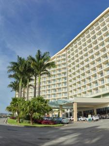 a large hotel with palm trees in a parking lot at Bourbon Resort Atibaia in Atibaia