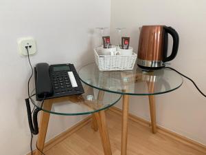 a glass table with a coffee maker and a telephone at Pansion Waldinger in Osijek