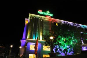 a building with a neon sign on top of it at Sai Neem Tree Hotel in Shirdi